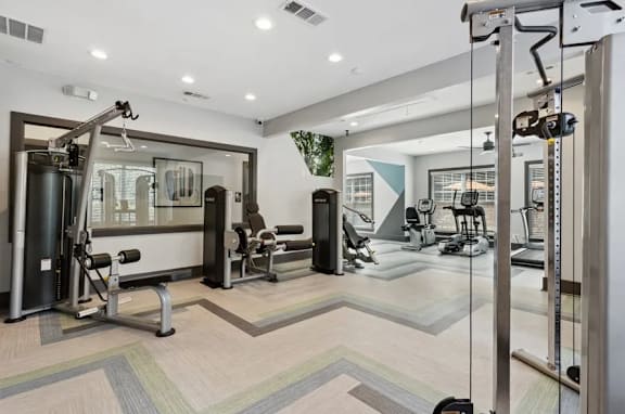 A spacious gym with a variety of equipment including treadmills, weights, and exercise machines at The Hartley at Sweetwater Creek, Duluth, Georgia, 30096