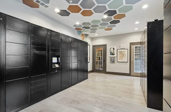 Package lockers with black doors and a patterned ceiling at The Hartley at Sweetwater Creek, Duluth, GA