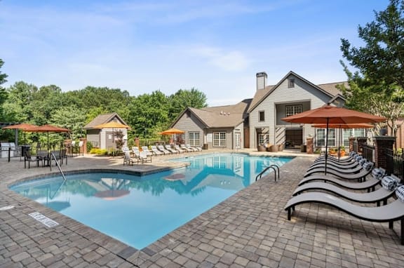 A large outdoor swimming pool with lounge chairs and umbrellas at The Hartley at Sweetwater Creek, Duluth, GA