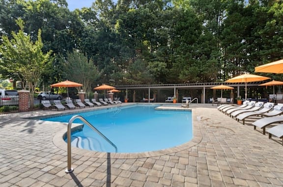 A large outdoor swimming pool surrounded by sun loungers and umbrellas at The Hartley at Sweetwater Creek, Duluth 30096