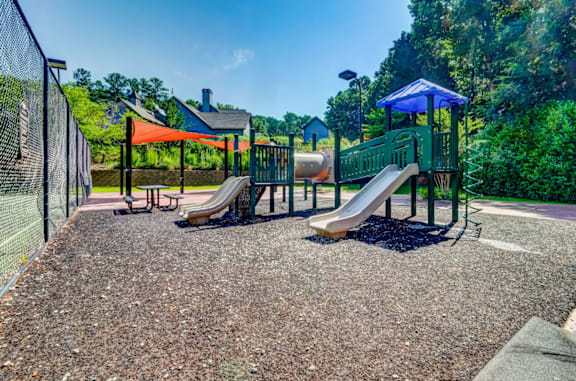 A playground with a slide and a blue canopy at The Hartley at Sweetwater Creek, Georgia 30096