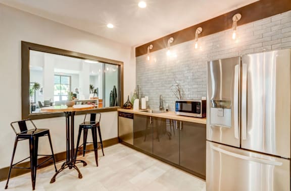 Community demonstration kitchen with a refrigerator, microwave, and bar stools at The Hartley at Sweetwater Creek, Duluth, GA