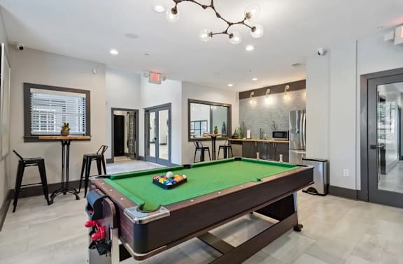 Community lounge with a pool table is in the middle of a room with a bar and a mirror at The Hartley at Sweetwater Creek, Duluth, Georgia