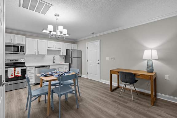 A kitchen with a dining table and chairs.