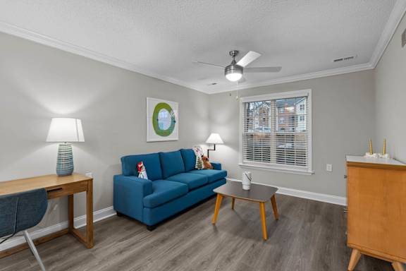 A living room with a blue couch and a ceiling fan.