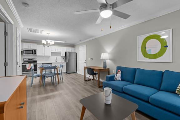A blue couch sits in a living room with a dining table and chairs.