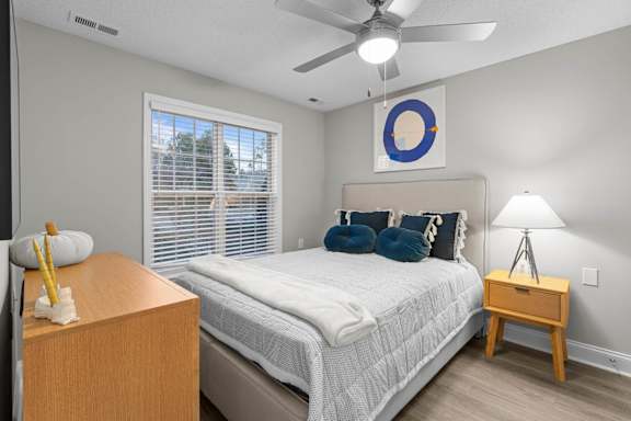 A bedroom with a bed, nightstand, and window.