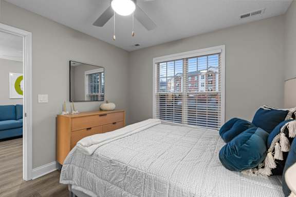 A bedroom with a large bed and a window with blinds.
