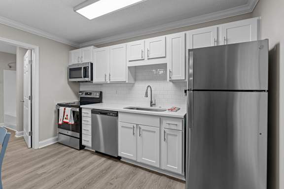 A kitchen with white cabinets and a stainless steel refrigerator.