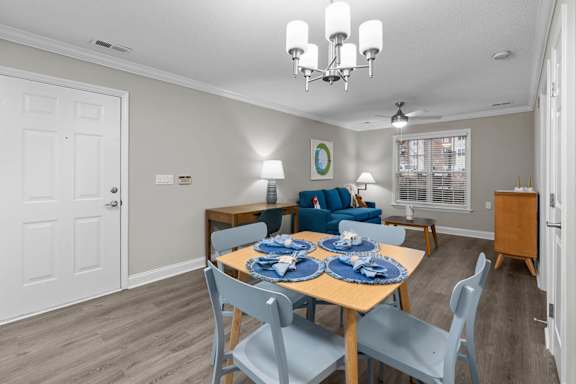 A dining room with a table set for two and chairs surrounding it.