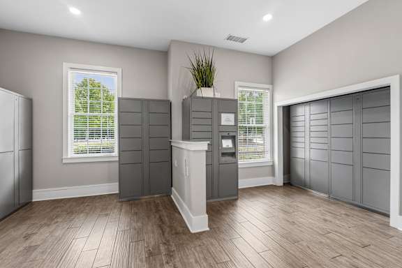A room with grey walls and wooden flooring with a white column in the middle.