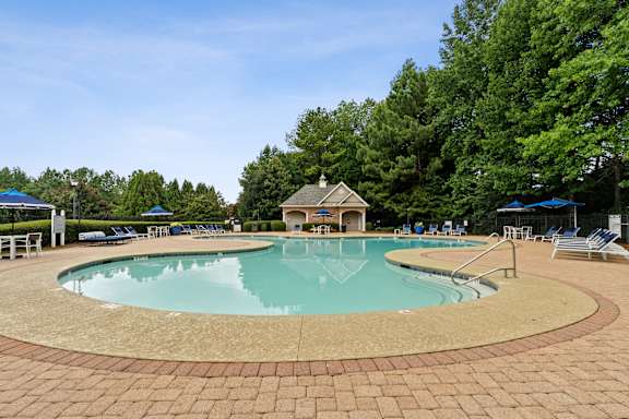 A large outdoor swimming pool surrounded by a brick patio.