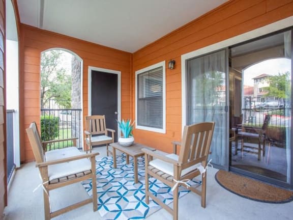 a porch with rocking chairs and a table and a sliding glass door