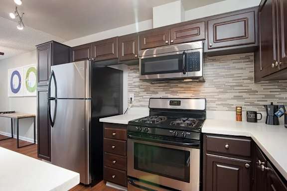 A modern kitchen with a stainless steel refrigerator, microwave, and oven.