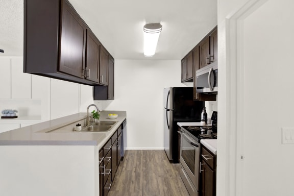 a kitchen with a sink and a stove and a refrigerator at Monterra Ridge Apartments, Canyon Country