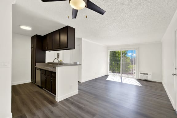 an empty kitchen and living room with a sliding glass door to a balcony at Monterra Ridge Apartments, Canyon Country