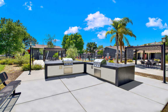 a patio with a grill and a table with chairs at Monterra Ridge Apartments, Canyon Country, California