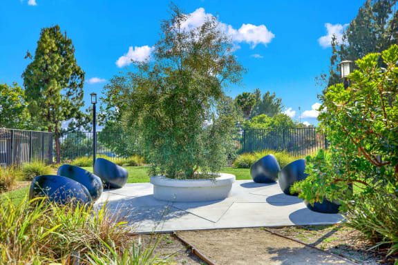 a seating area in a garden with trees and plants at Monterra Ridge Apartments, California,91351