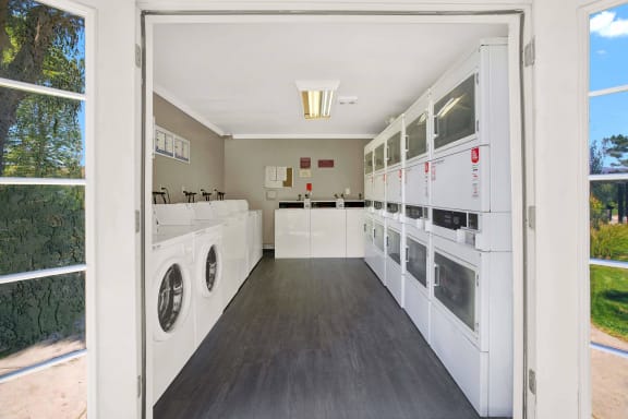 a laundry room with washers and dryers and a door open at Monterra Ridge Apartments, Canyon Country ,91351
