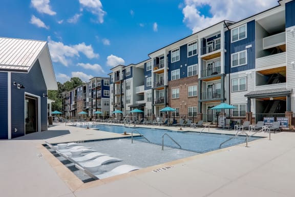 a swimming pool with umbrellas in front of an apartment building