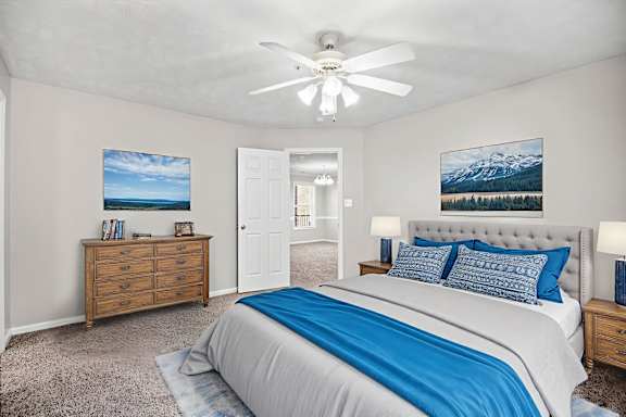 A bedroom with a bed, nightstand, and a ceiling fan.