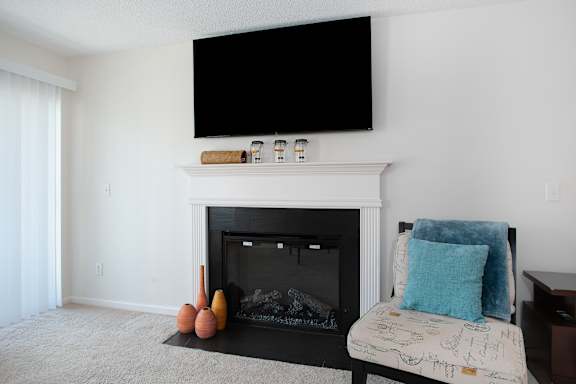 A living room with a fireplace, a sofa and a television mounted above it.