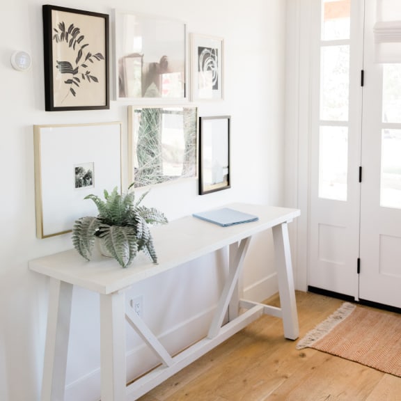 a white desk with a plant and pictures on the wall