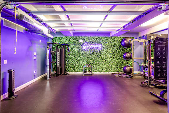 A gym with purple lighting and a green wall with the word "Supreme" on it.
