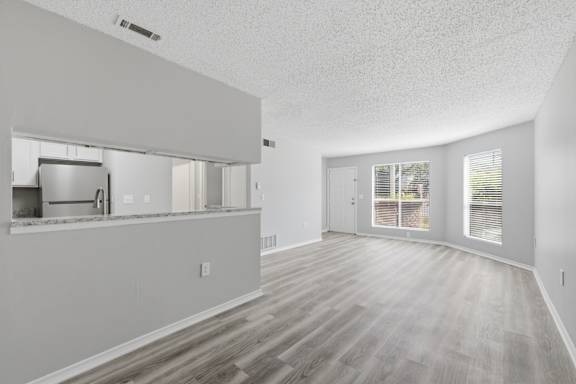 A spacious room with wooden flooring and white walls.