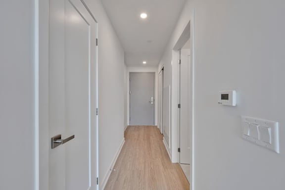 A long hallway with white walls and wood floors.