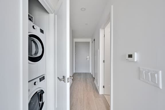A modern laundry room with a washing machine and a hallway.