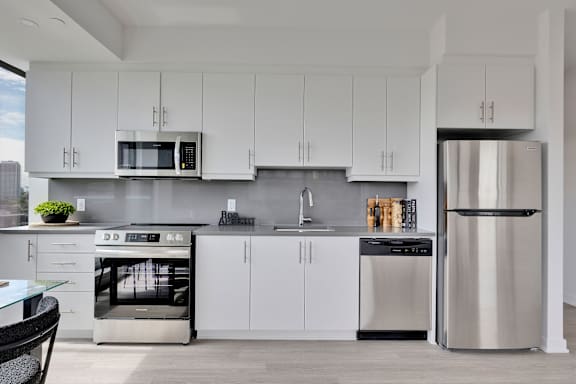 A modern kitchen with white cabinets and stainless steel appliances.