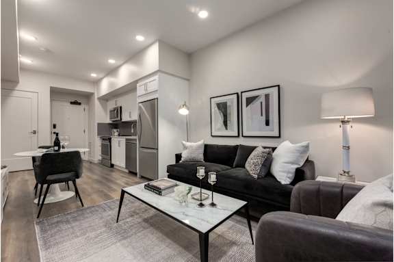A modern living room with a black couch and a glass coffee table.
