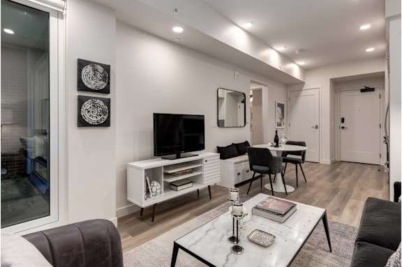 A modern living room with a grey sofa, a white coffee table, and a television.