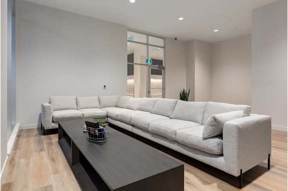 A white sofa with a black coffee table in front of it.