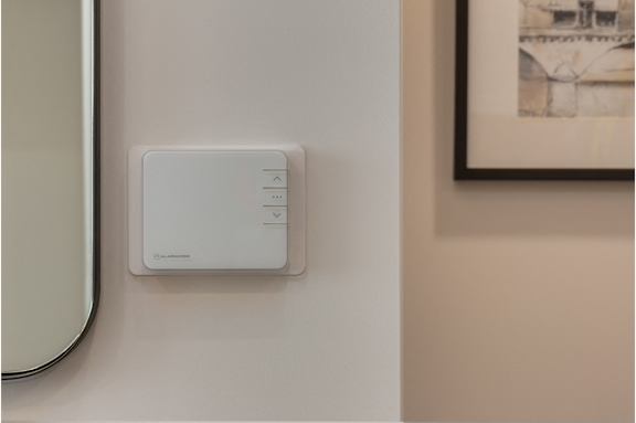 A white device with buttons is mounted on a wall.