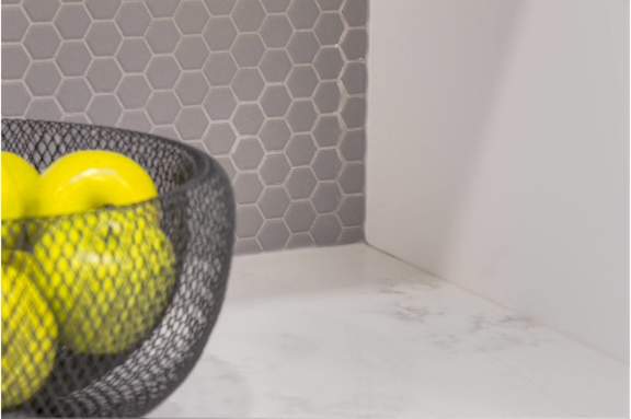 A black wire basket with three yellow balls inside.