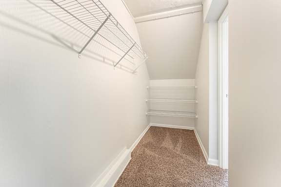 A white wall with a brown carpeted floor and a white door.