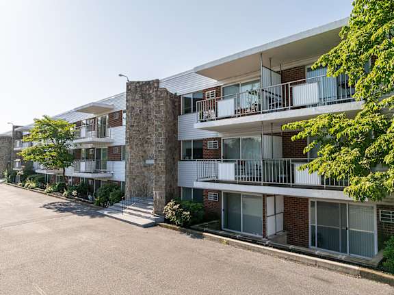 A multi-story residential building with a stone pillar in the foreground.