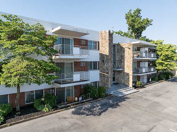 A multi-story apartment building with a parking lot in front.