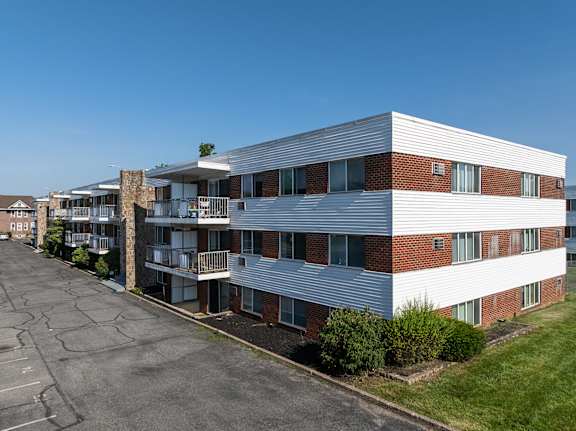A large apartment complex with a parking lot in front.