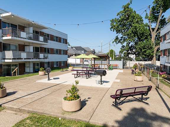 A sunny day at the courtyard of a residential building with benches and potted plants.
