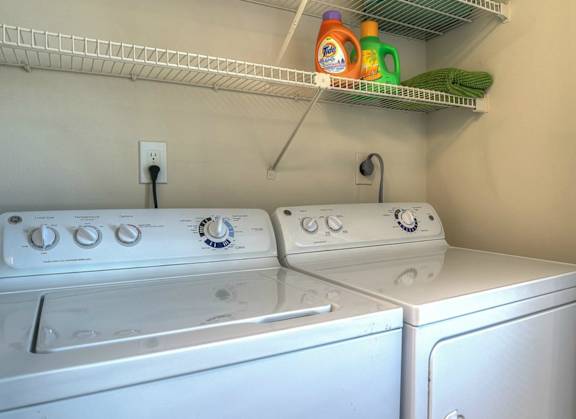 In-unit washer and dryer at Town Place Apartments with convenient shelving for everyday laundry and extra storage.