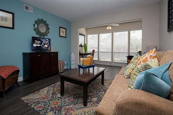 Connected sunroom and open living room at Town Place Apartments, with a ceiling fan in the sunroom, abundant natural light, and a spacious, flexible floor plan.