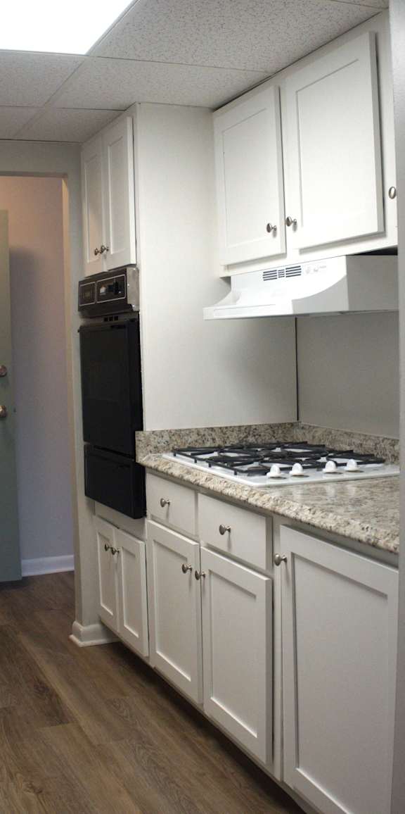 a kitchen with white cabinets and a stove and black refrigerator