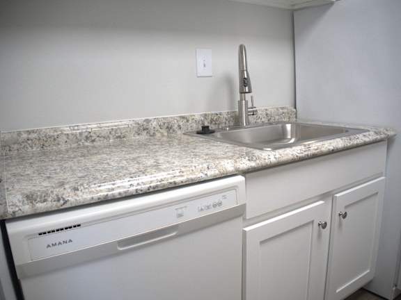 a kitchen with white cabinets and granite counter tops and a sink