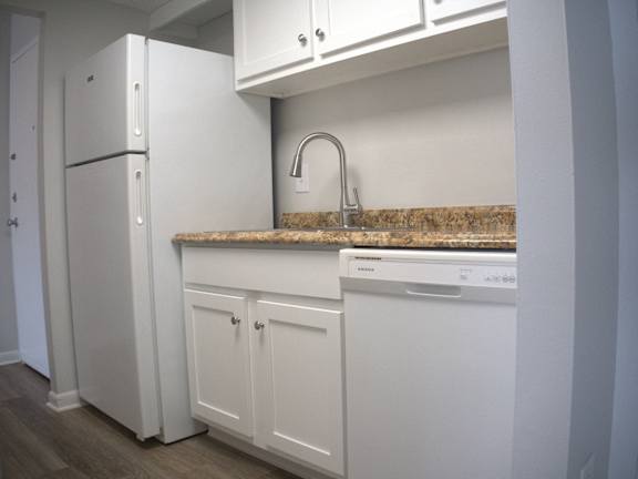 a kitchen with white cabinets and a sink and a refrigerator