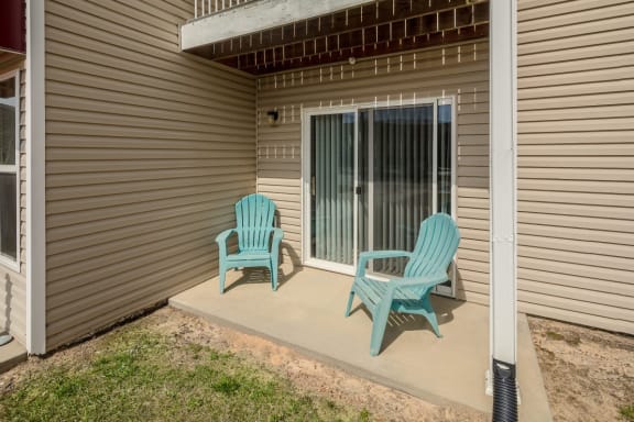 two blue chairs sit on a patio in front of a sliding glass door