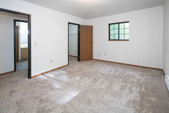 an empty living room with carpet and a door to a bathroom