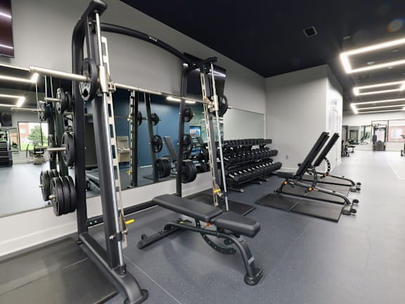 A gym with a variety of equipment including weight machines and dumbbells.